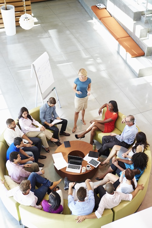 Businesswoman presenting to a group of professionals seated around a table